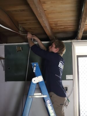 EWJ Electrical electrician fitting a garage light to the ceiling from a ladder in Brisbane