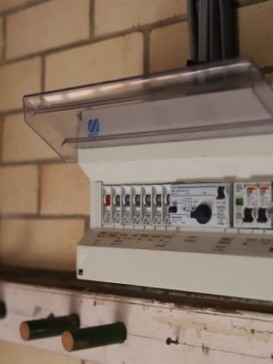 Switchboard with the cover open on a brick garage wall in Brisbane